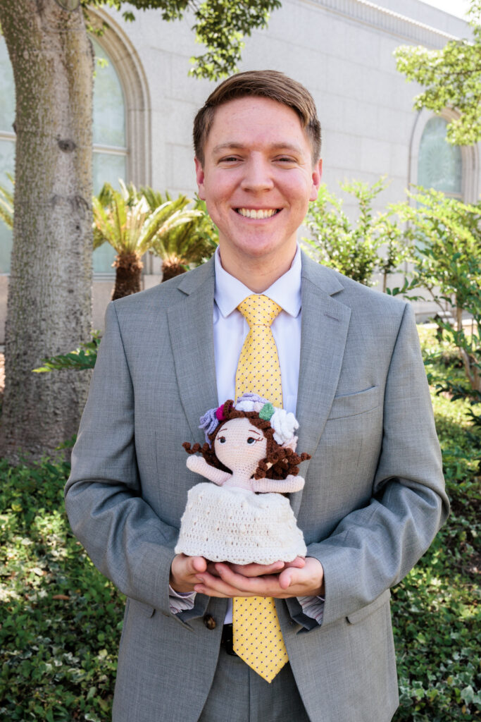 Groom stands with Bride's unique doll floral arrangement outside the Redlands LDS temple on their wedding day.