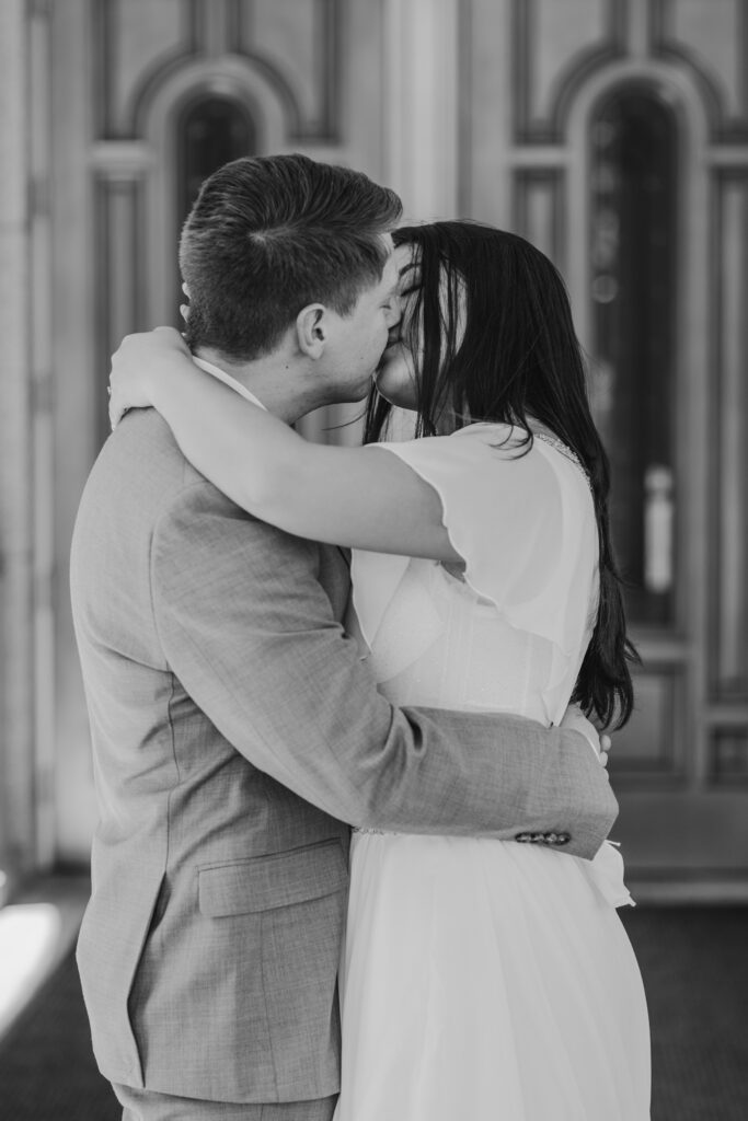 black and white photo of a couple kissing in front of the doors of the Redlands Mormon LDS Temple in California.