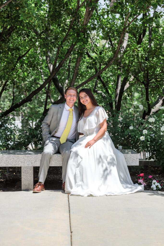 Couple sits on a bench outside the Redlands California LDS temple on their wedding day.