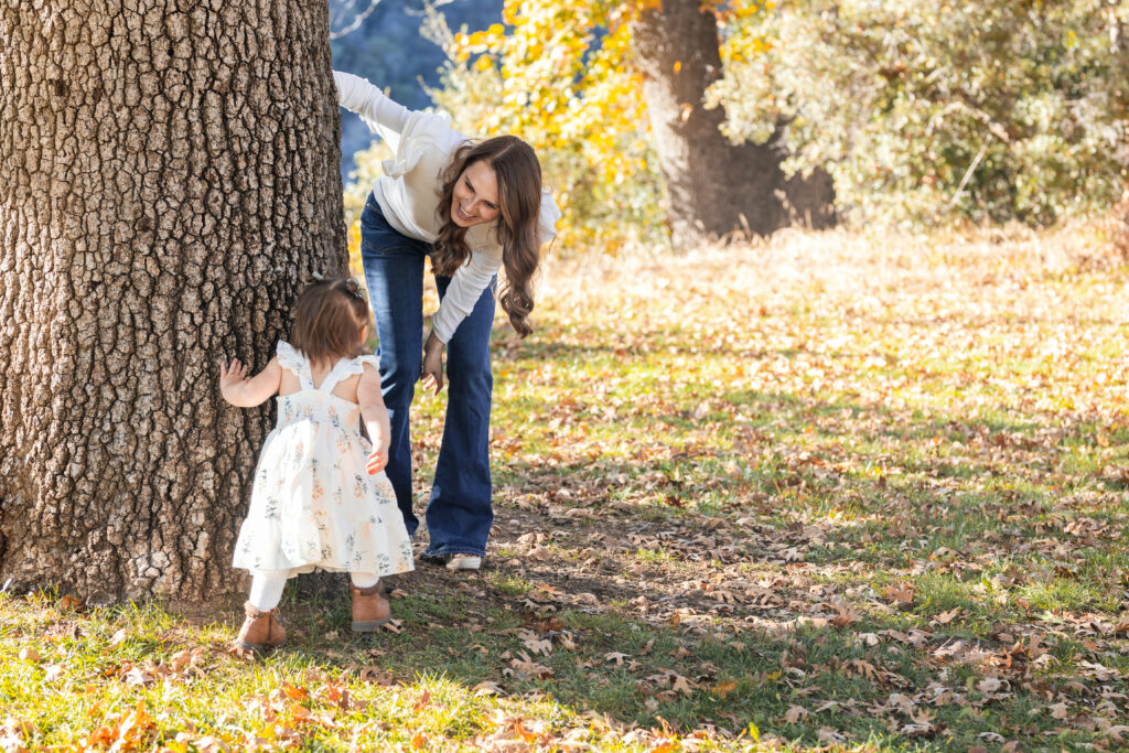 Mom and kid play around a large tree in Oak Glen, CA.