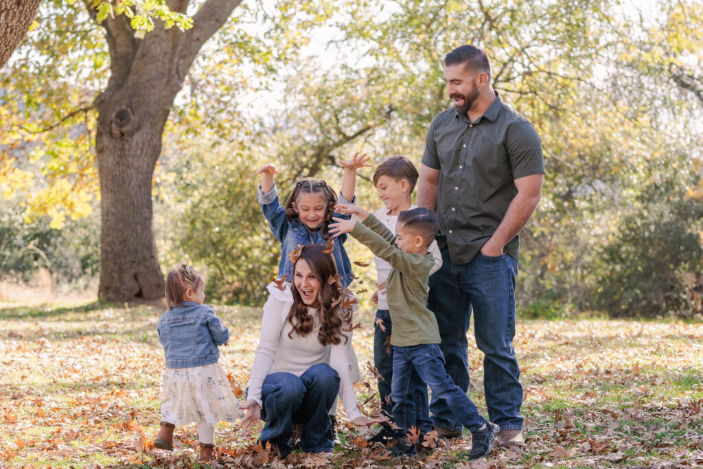 Family throwing leaves on mom in Oak Glen, CA for photoshoot. 