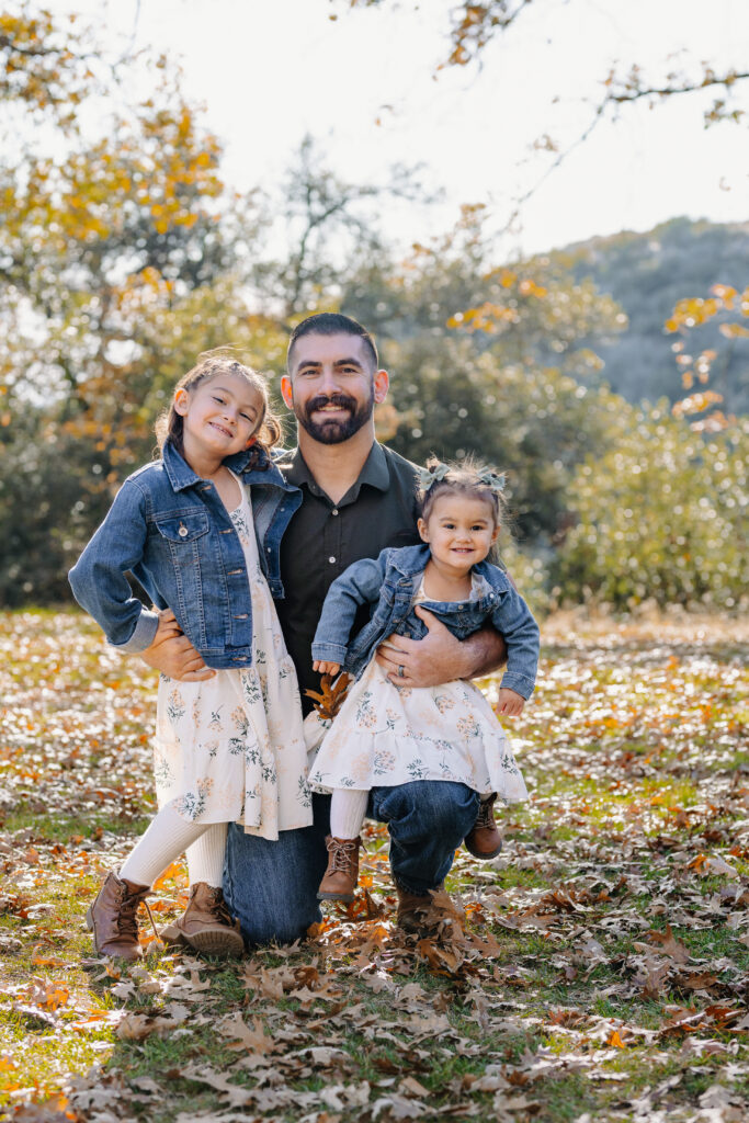 Proud dad and daughters smiling in Oak Glen, CA for photoshoot. 